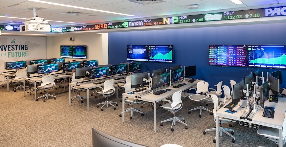 interior of a finance lab at Babson College, where many desks hold computer monitors showing stock market exchange displays